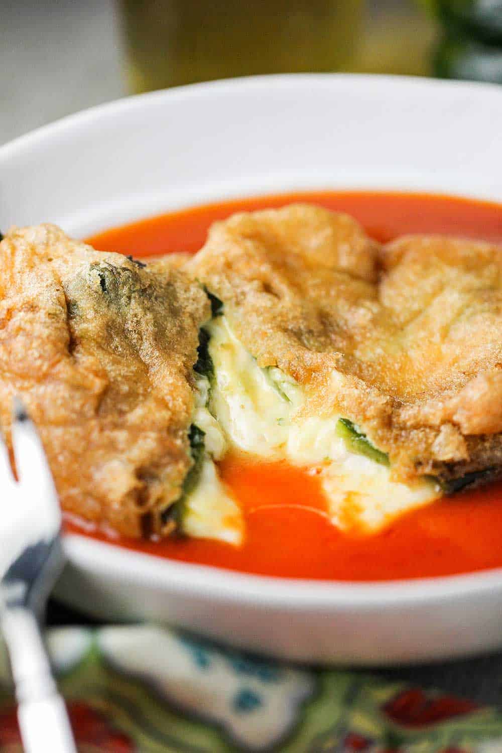 Chile rellenos that is cut in half in a white bowl.
