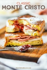 A Monte Cristo sandwich that has been sliced in half and then stacked, with a smear of preserves in the middle and a bite taken out.