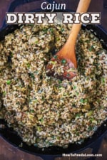 An overhead view of a large black cast-iron skillet filled with Cajun dirty rice with a big wooden spoon inserted into the middle of it.