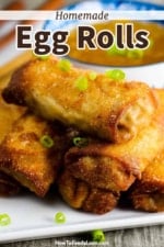 A plate filled with homemade egg rolls with chopped scallions sprinkled on top.