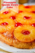 A close up view of a pineapple upside-down cake on a white platter.