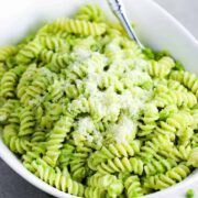 Fresh pea pesto pasta in a white serving bowl with a spoon