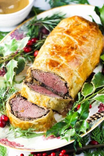 Classic Beef Wellington on a platter with Christmas holly around it