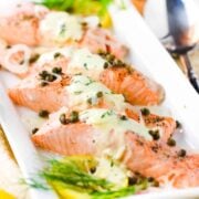 Poached salmon with capers and hollandaise sauce on a white platter