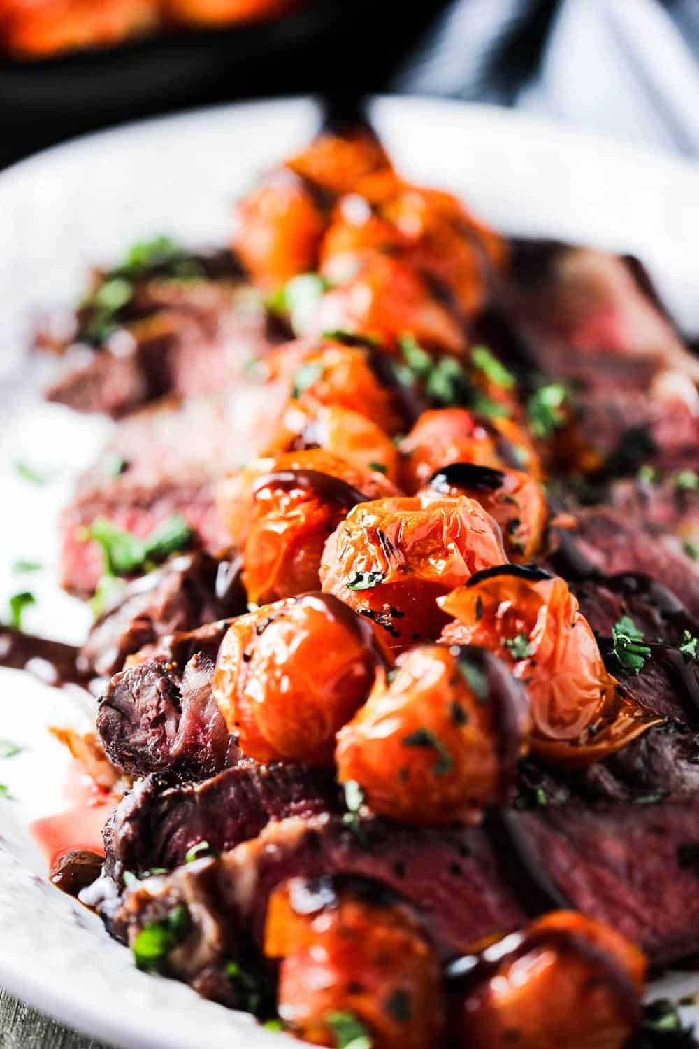 Seared ribeye with blistered tomatoes and bordelaise sauce on a platter