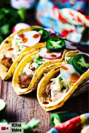 Mahi Mahi tacos on a wooden table in a taco holder