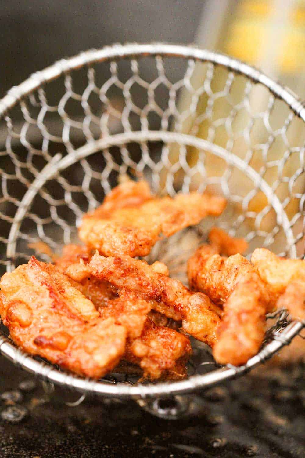 Deep fried pork strips in a metal spatula for Sweet and Sour Pork.