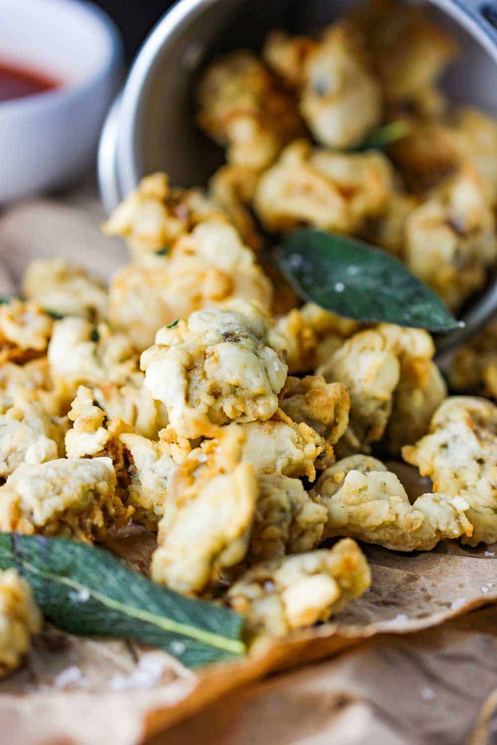 Fried oysters and littleneck clams with fried sage tumbling out of a sliver pale.