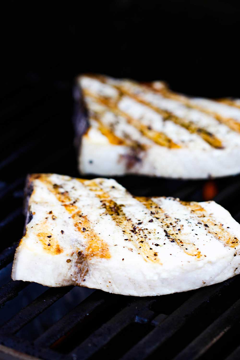 Two swordfish steaks on a hot grill.