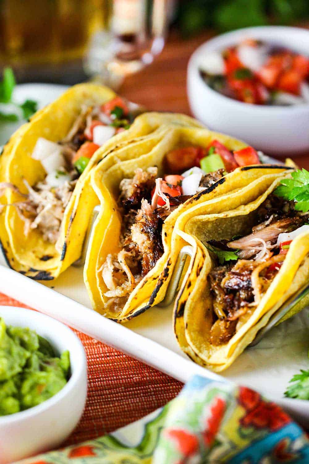 Stack three carnitas tacos on a taco stand.