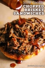 Homemade barbecue sauce being drizzled out of a glass bottle onto chopped brisket that is sitting on a toasted bun.