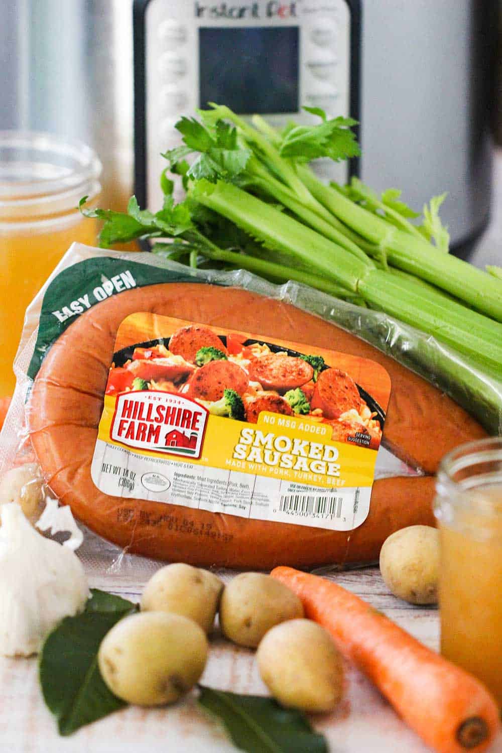 A package of smoked sausage with fresh vegetables in front of an Instant Pot.