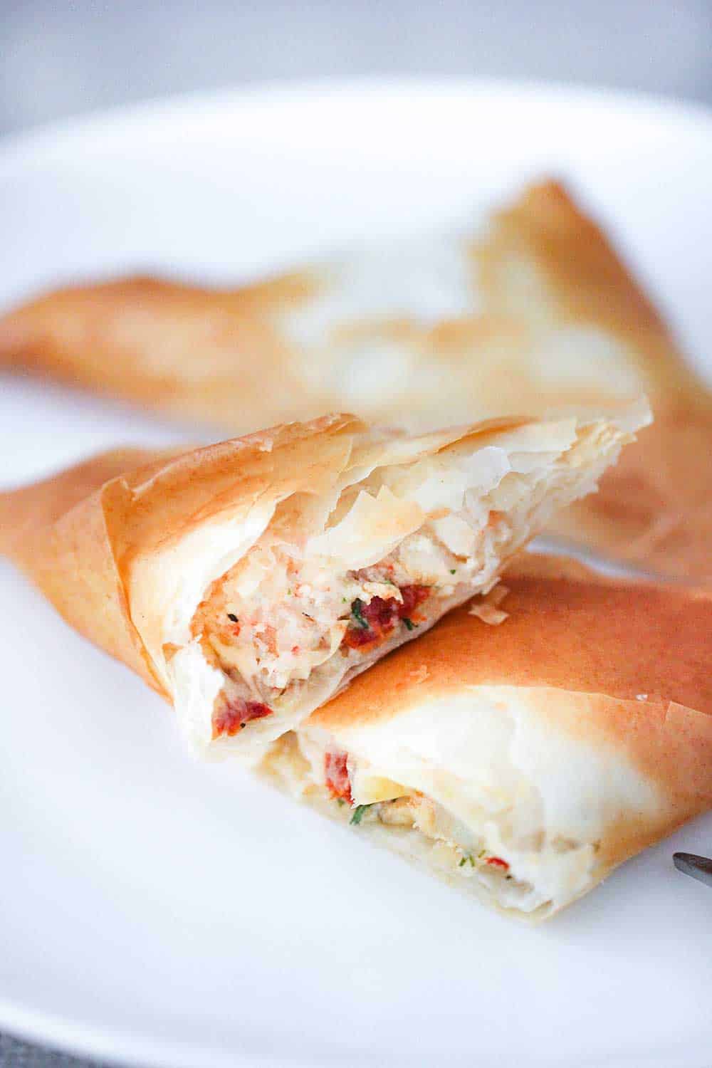 A split open air fryer shrimp and artichoke phyllo triangle on a cocktail plate.