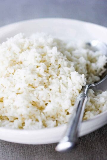 A white bowl of perfect steamed rice with a spoon in it.