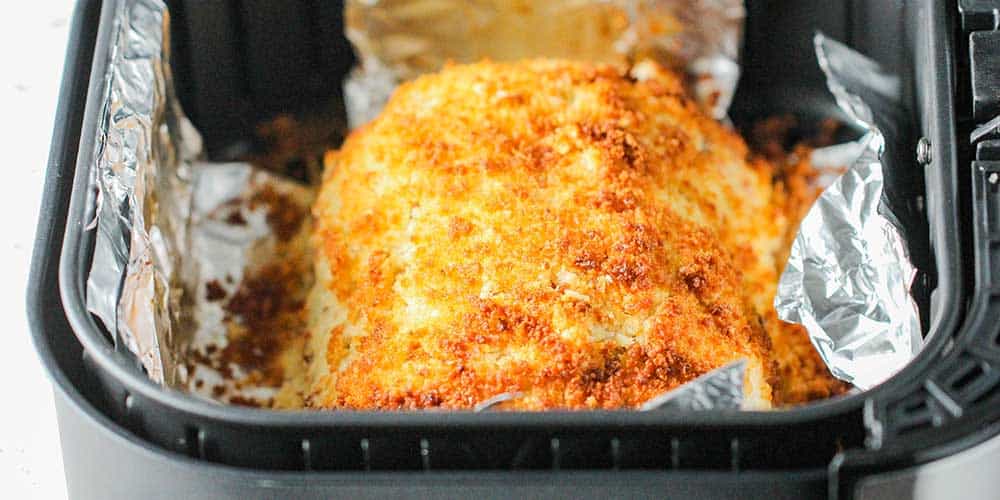 A golden loaf of cordon bleu in the basket of an air fryer.