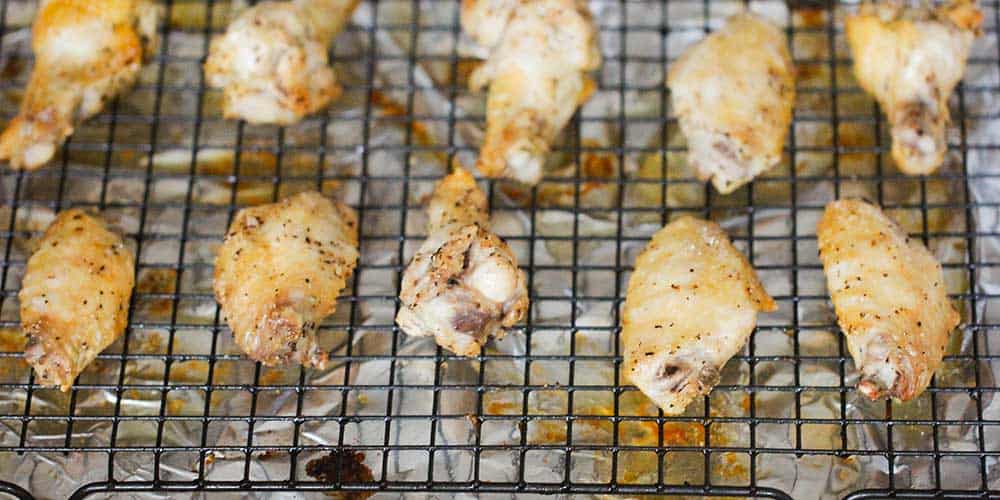 A baking pan lined with a baking rack topped with baked hot wings.