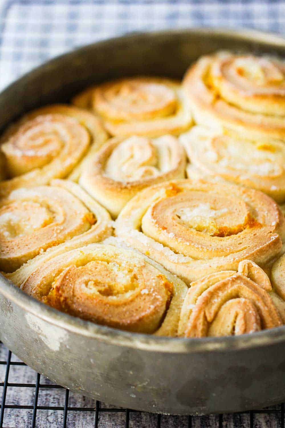 A circular metal pan holding freshly baked orange sweet rolls.