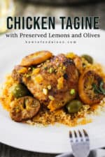 A white plate filled with chicken tagine with preserved lemons and olives with a fork resting on the plate.