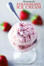 An overhead view of a glass bowl with a stem holding a serving of homemade strawberry ice cream with whole strawberries scattered around next to it.