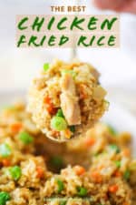 A large spoon holding a helping of chicken fried rice over a bowl of the dish.