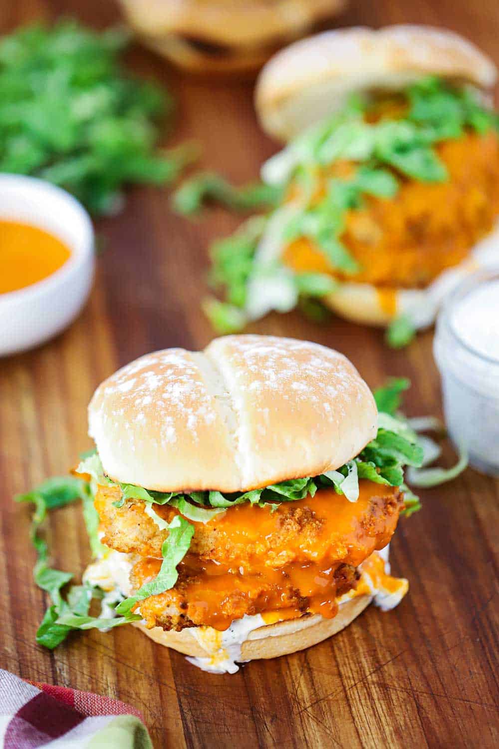 A buffalo chicken sandwich on toasted buns with shredded lettuce under the top bun.