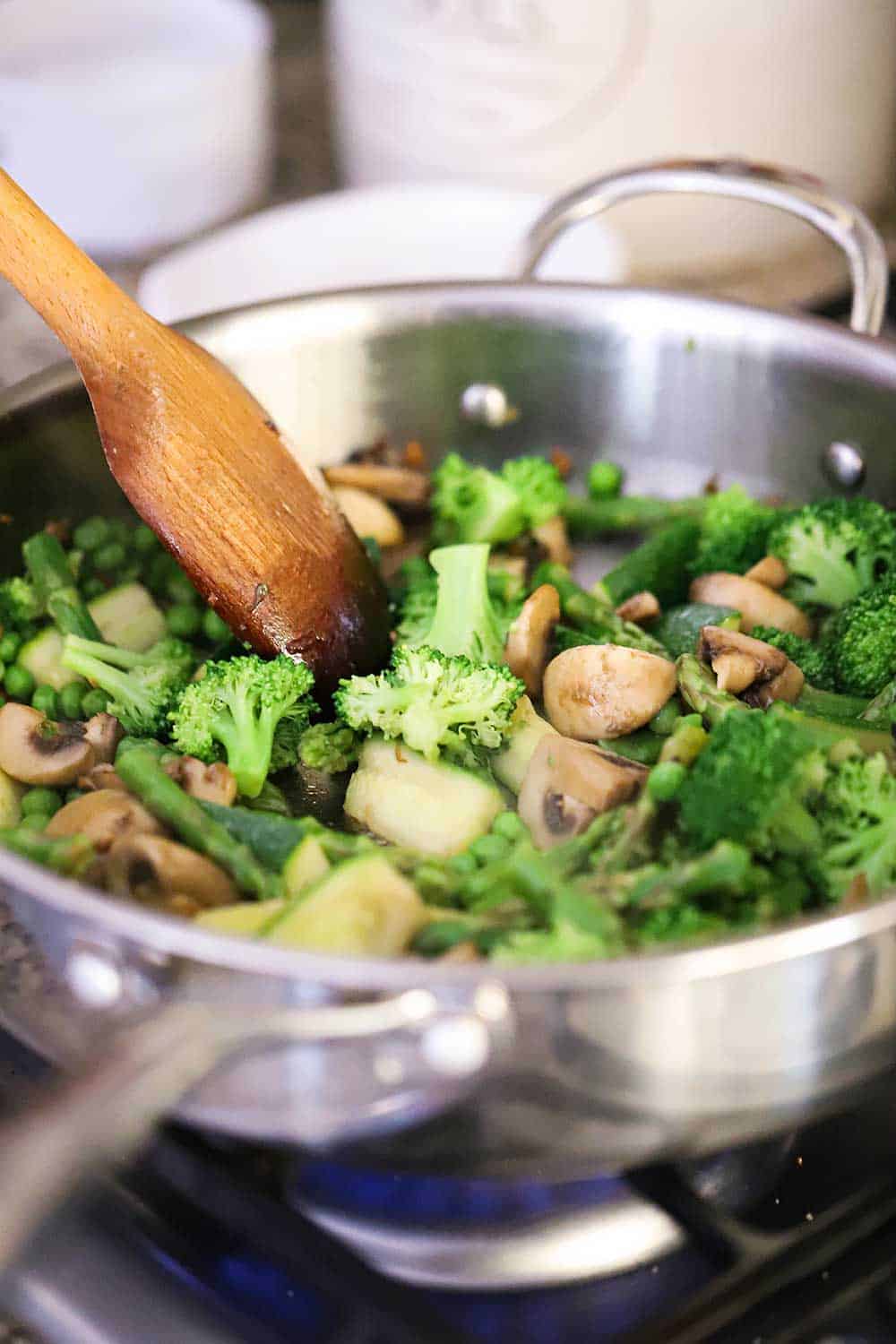 A large stainless steel skillet filled with sauteed broccoli and mushrooms.