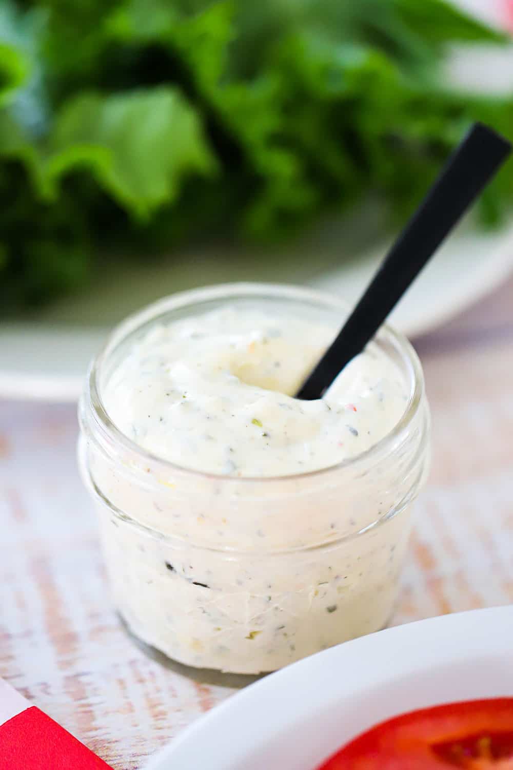 A small jar filled with chimichurri mayonnaise with a small spoon stuck in it.