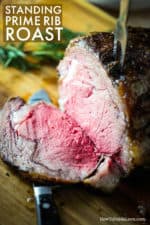 A large standing prime rib roast on a cutting board with a slice cut away from the roast.