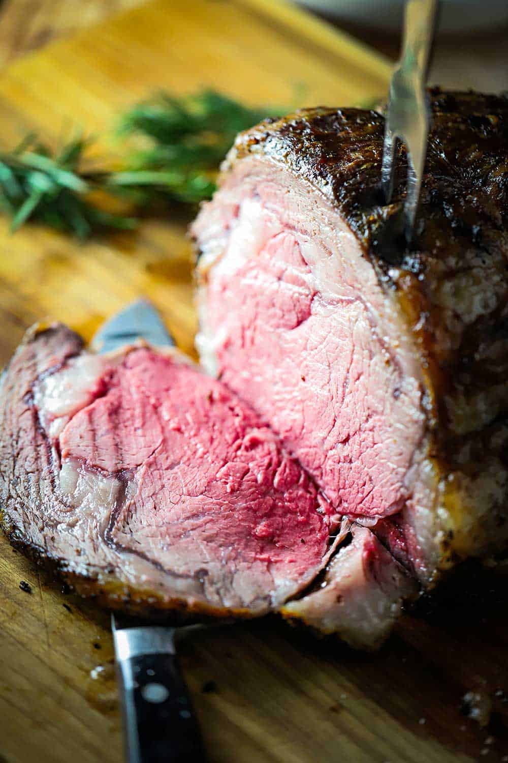 A large beef roast on a cutting board with a slice cut away from the roast.