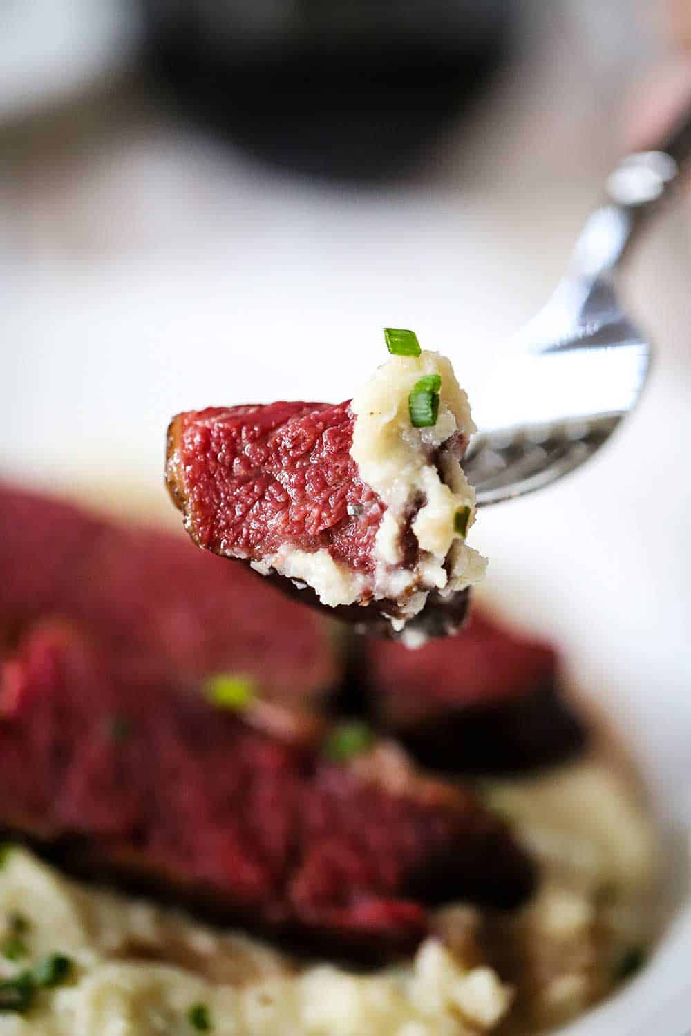 A fork being held up with a piece of Wagyu short ribs on the end of it.