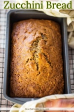 A pair of hands using two kitchen linens to hold a pan filled with freshly baked zucchini bread.