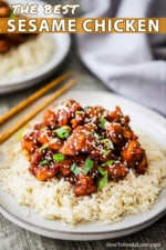 A dinner plate filled with a bed of white rice with sesame chicken on top of it and a pair of chop sticks nearby.