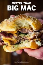 A pair of hands holding a homemade Big Mac hamburger with a bite taken out it.