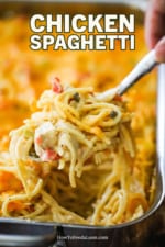 A spoon lifting a helping of chicken spaghetti out of a large lasagna pan.