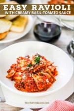 An individual white pasta bowl filled with ravioli and a tomato sauce next to a stemless wine glass filled with red wine and a plate of garlic bread nearby.