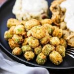 A blue dinner plate willed with chicken fried steak, mashed potatoes, both topped with gravy, all next to a pile of fried okra.