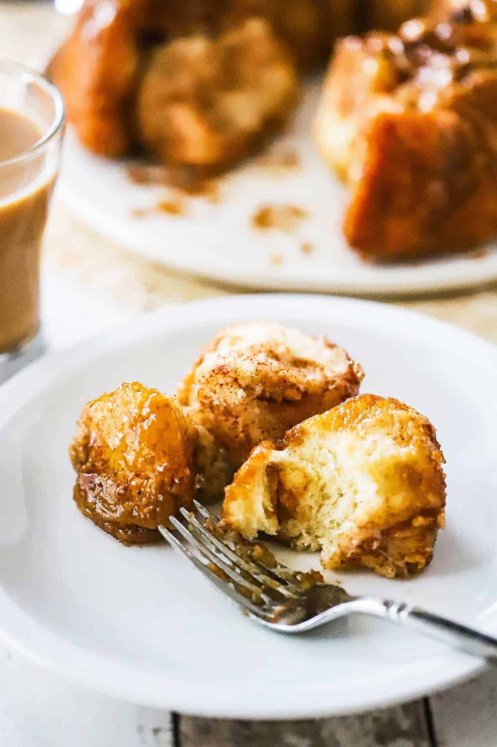 A small white plate holding several pieces of monkey bread and a silver fork.