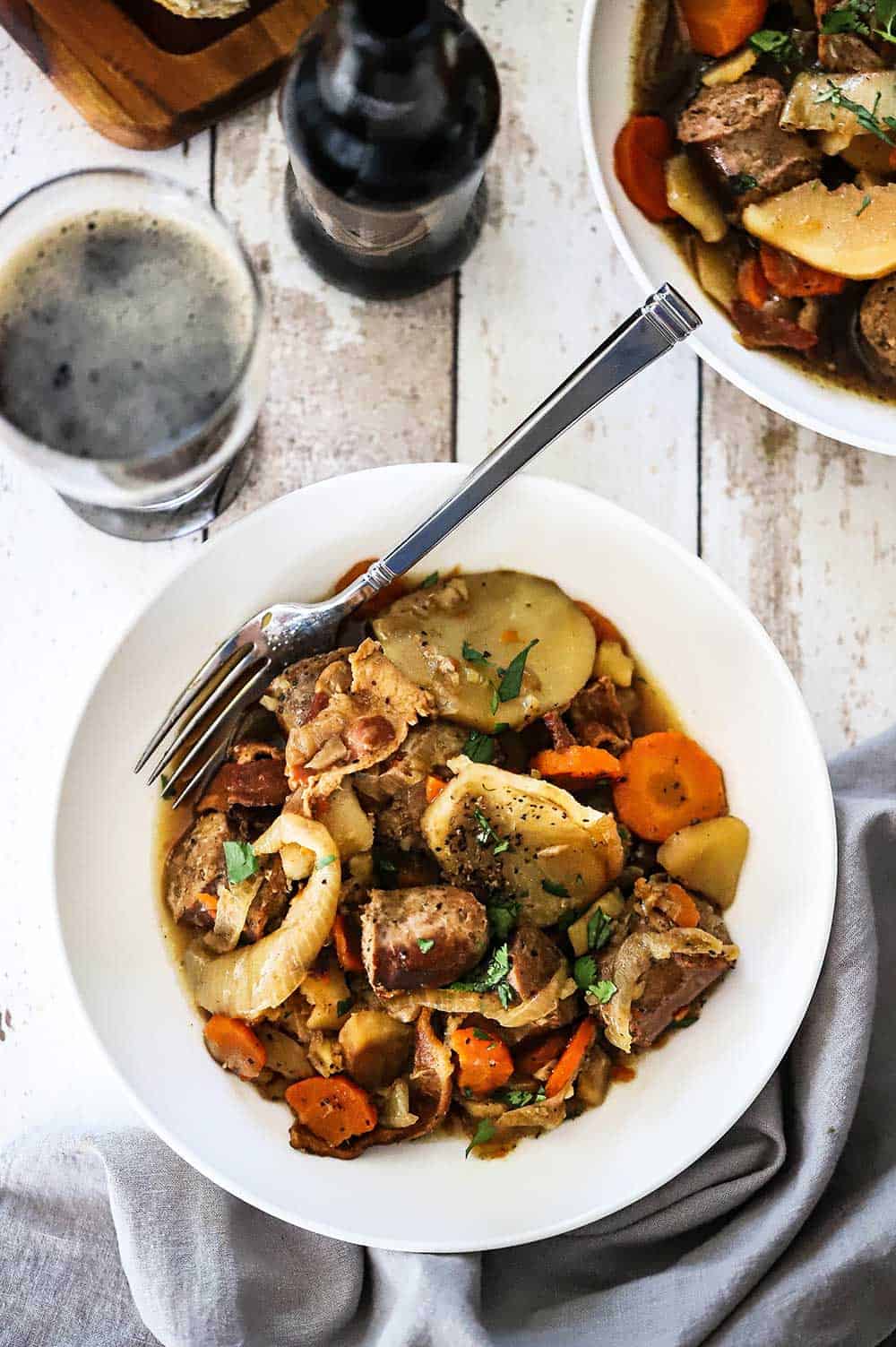 A white bowl filled with Dublin Coddle with a fork inserted in the side.
