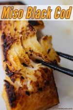 A close-up view of a pair of chop stick flaking a piece of black cod that has been fully cooked