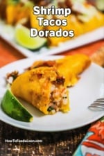 A fried shrimp taco sitting on a plate with a bite taken out of it.