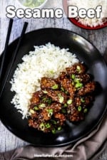 An overhead view of a dark plate that is filled with crispy sesame beef and rice.