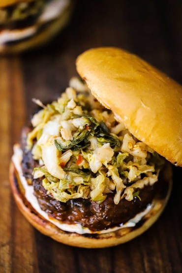An overhead view of a bulgogi burger that is topped with easy kimchi all on a toasted brioche bun.