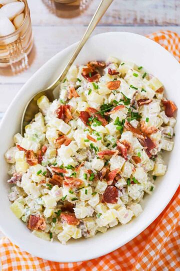 An overhead view of an oval serving bowl filled with creamy horseradish potato salad.