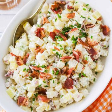 An overhead view of an oval serving bowl filled with creamy horseradish potato salad.