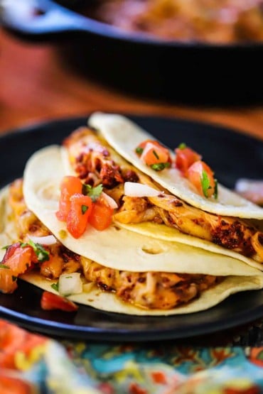 Two flour tortillas that are folded over melted cheese and chorizo and topped with chopped tomatoes, onion, and cilantro.