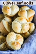 A close-up view of a basket lined with a blue cloth and filled with cloverleaf dinner rolls.