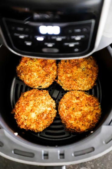 An overhead view of four eggplant medallions that have been breaded and air fried and are sitting in the air fryer basket.