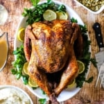 An overhead view of a deep-fried turkey sitting on a platter surrounds by other holiday side dishes.