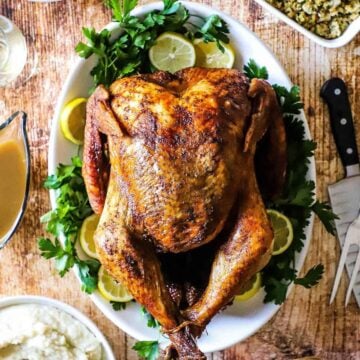 An overhead view of a deep-fried turkey sitting on a platter surrounds by other holiday side dishes.