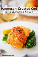A white dinner plate filled with Parmesan crusted cod with romesco resting on sautéd broccolini.